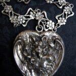 Bat Woman heart-shaped photo locket made by Unger Brothers, paired with a handmade antique silver French Art Nouveau sautoir chain with floral filigree design, circa 1900.