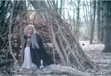 Winter Enchantment: Ceramicist Rachael Platt holding a lit manifesting jar under the full moon, surrounded by illuminated jars in a forest setting. Photography by steve parke